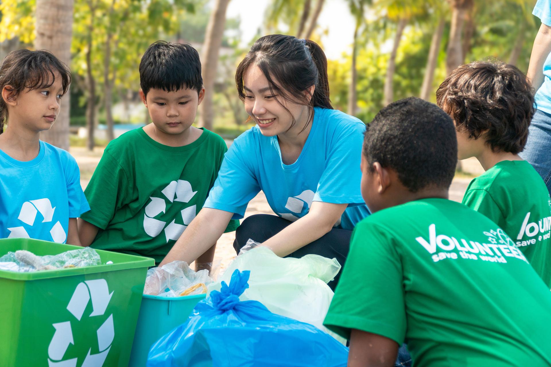 Group of kids school volunteer charity with garbage bags cleaning up on the beach.