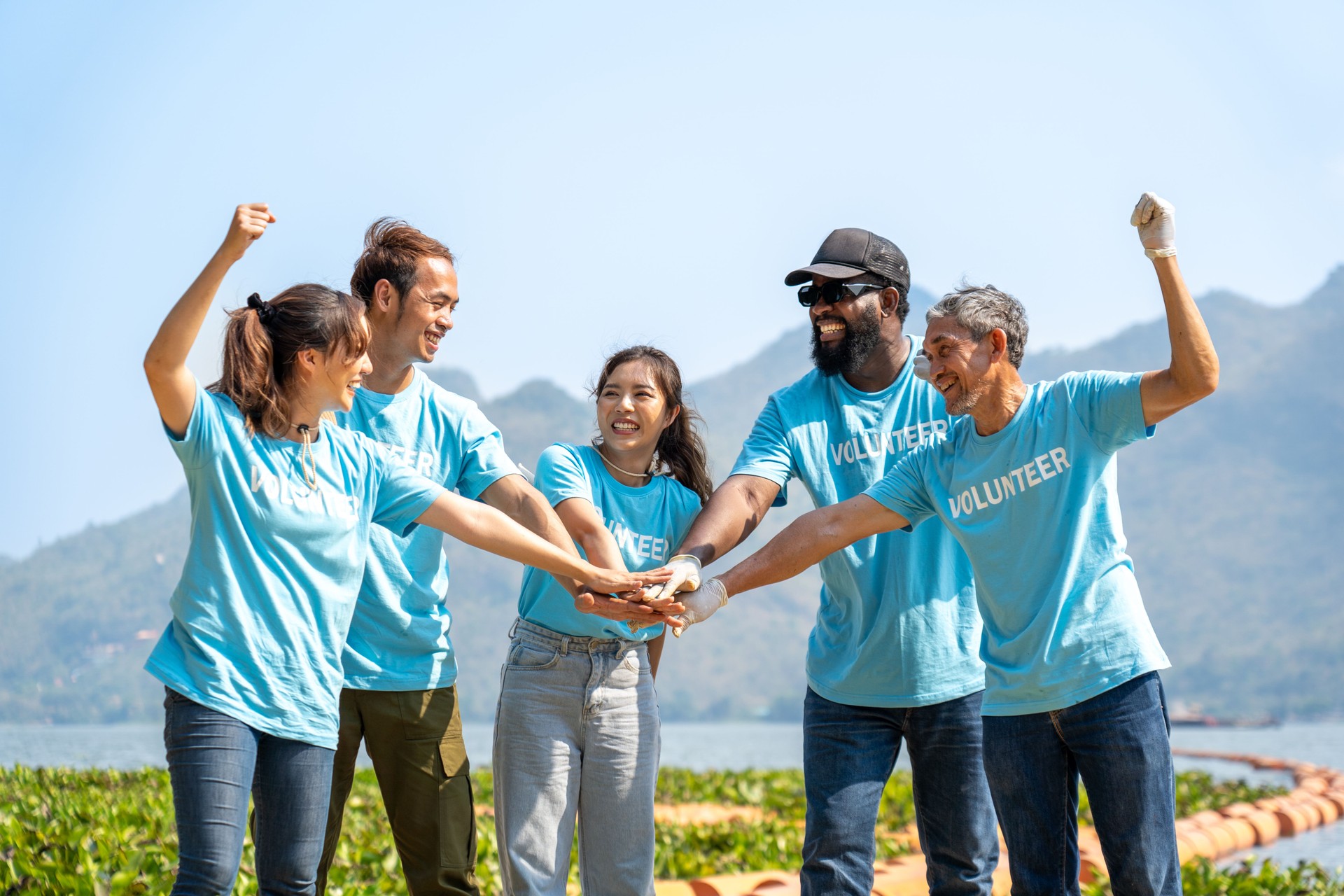 Group of happy volunteers joining hands stack together and raising hands with smile